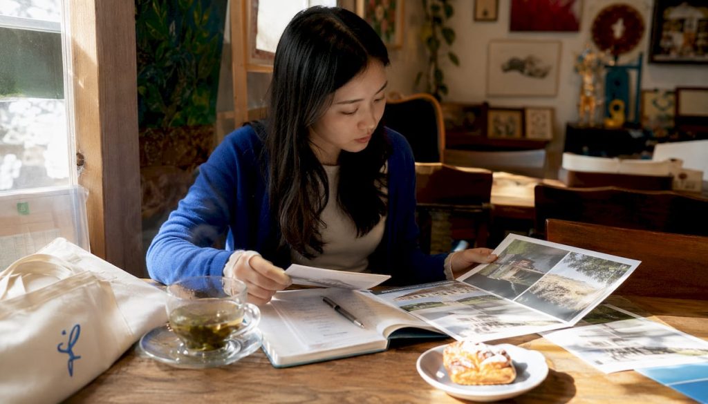 Young woman reviewing language course brochures at home