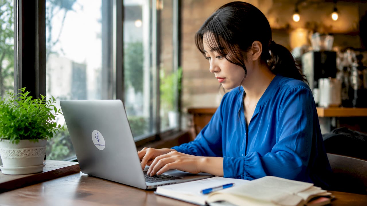 Hands typing Japanese business email on laptop keyboard