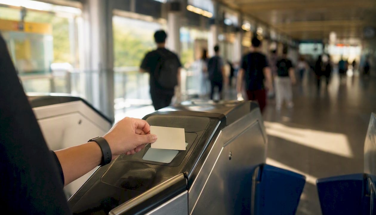 Hand holding MRT card at station gate