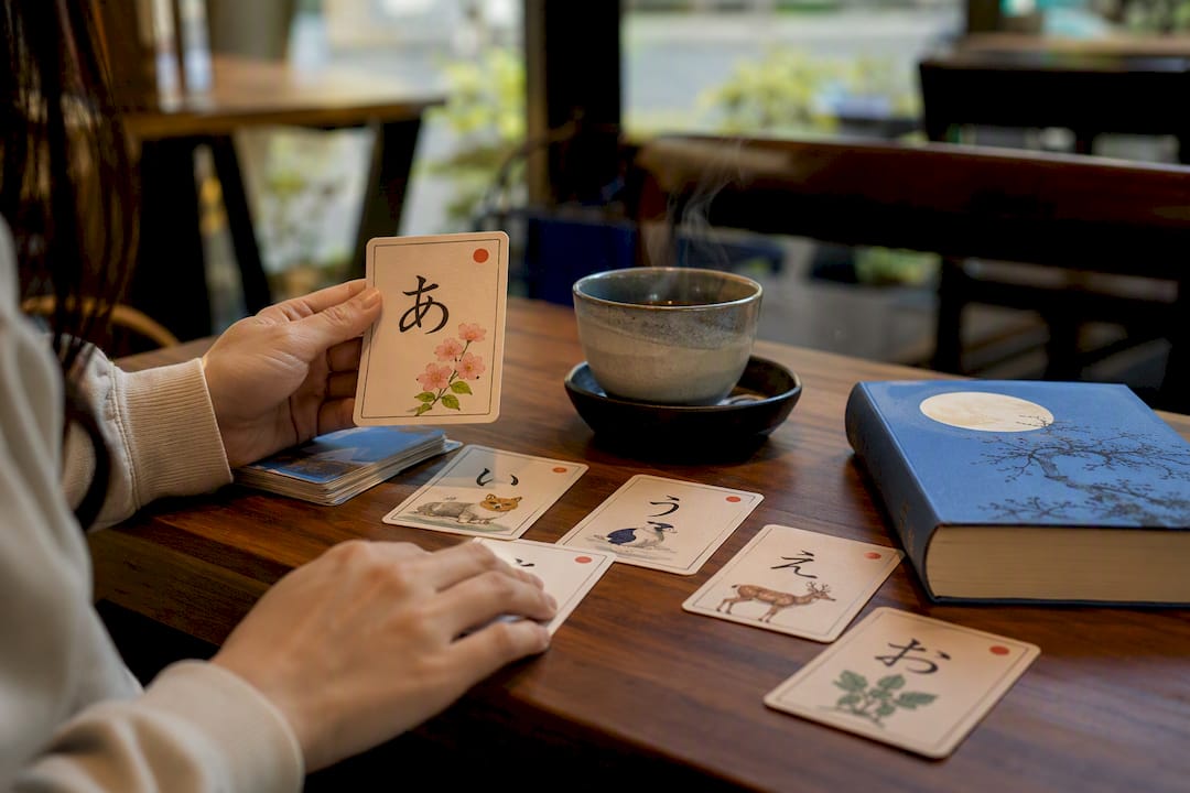 Hands holding Japanese kana flashcards on desk