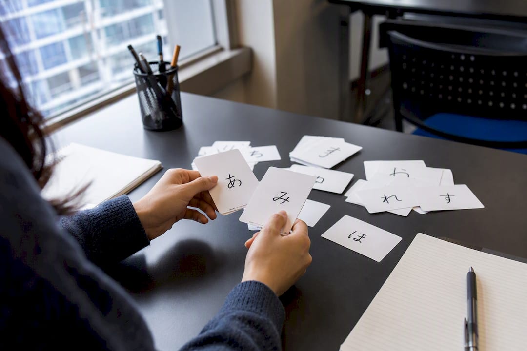 Hands holding Japanese flashcards on desk